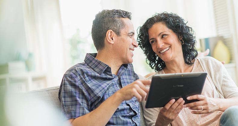 Happy couple looking at their tablet device | Tetra Images/Getty Images
